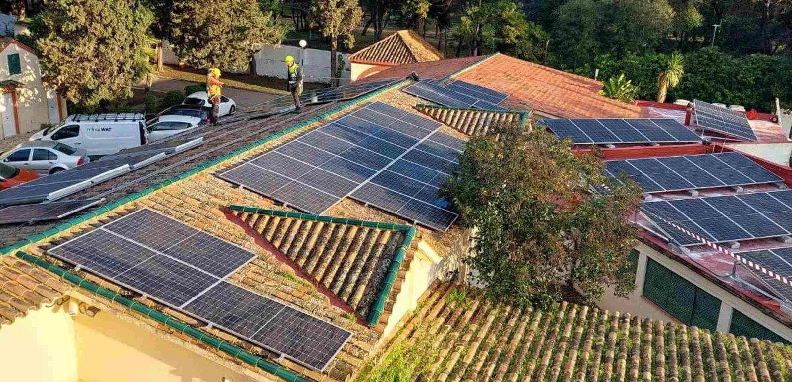 Dos operararios instalan placas solares en los tejados de un edificio. Dos operararios instalan placas solares en los tejados de un edificio.