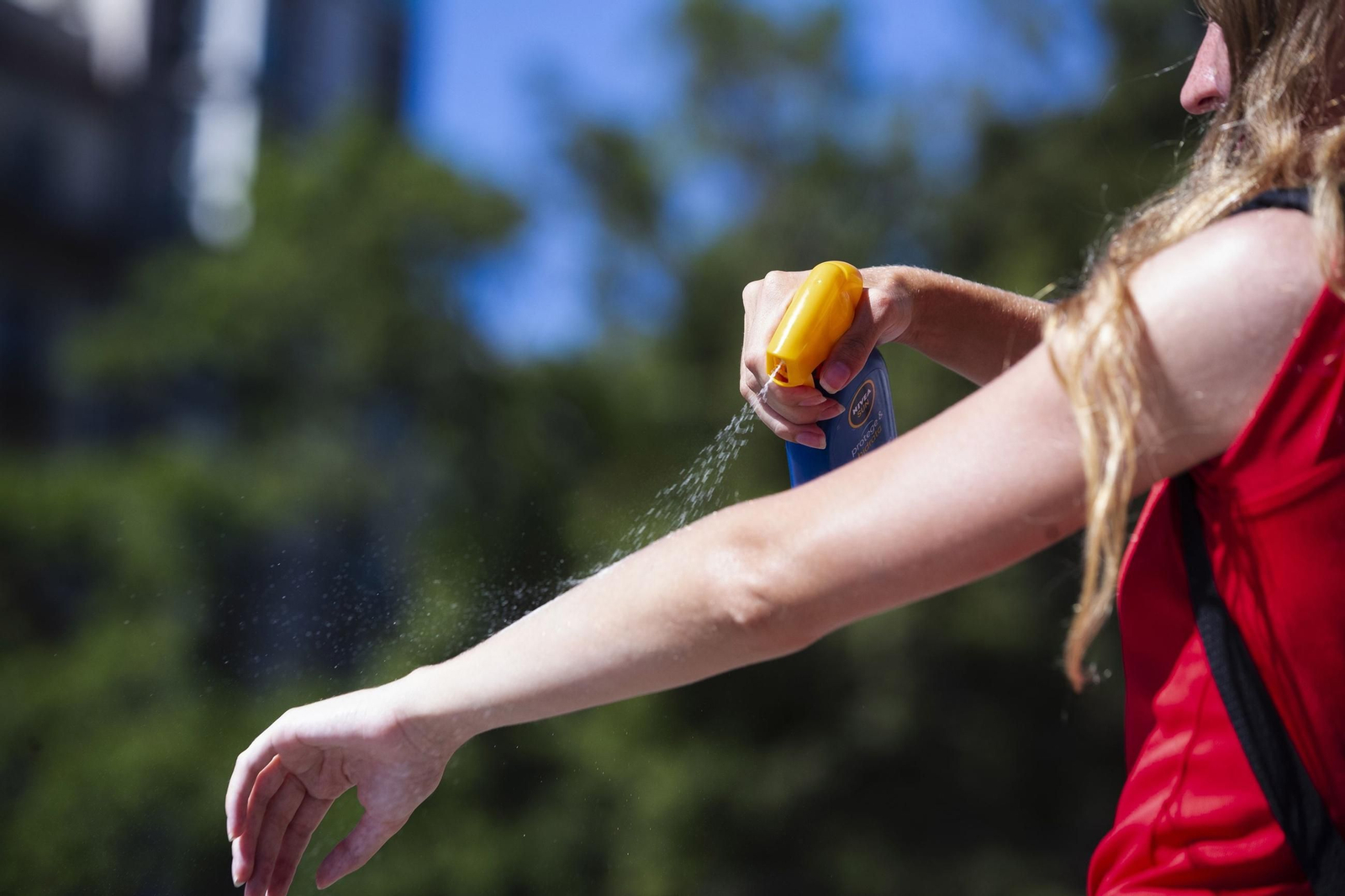 Una imagen de una mujer echándose crema solar. Una imagen de una mujer echándose crema solar.